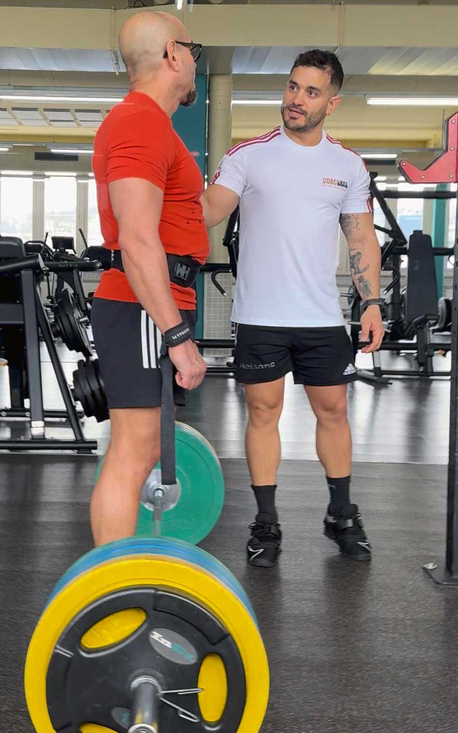 Coach Ray, Personal Trainer Konstanz, im Fitness-Studio beim Personal Training im Gewichtheben für einen Kunde.